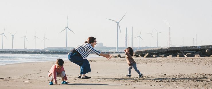 family on beach with windmills in background